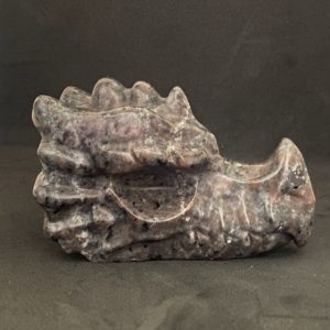Vue de profil d'une tête de dragon sculptée en Yooperlite fluorescente sous lumière UV