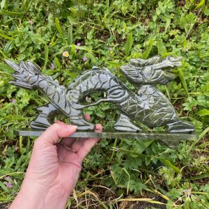 Sculpture de dragon complet en jade vert sur socle, corps sinueux et détails artisanaux, tenue à la main en extérieur.