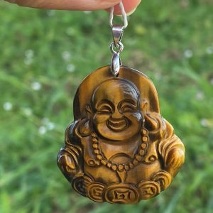 Pendentif sculpté en forme de Bouddha assis en œil de tigre naturel, avec reflets dorés et marron, monté sur une bélière robuste en acier inoxydable argenté.