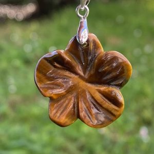 Pendentif en pierre naturelle d'œil de tigre sculpté en forme de fleur délicate, présentant des reflets chatoyants marron et dorés, monté sur une bélière discrète.