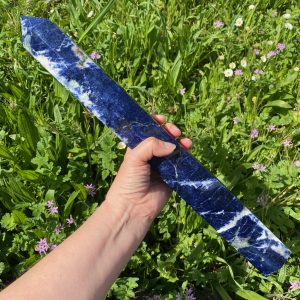 Tour de sodalite bleue naturelle polie posée dans un jardin.