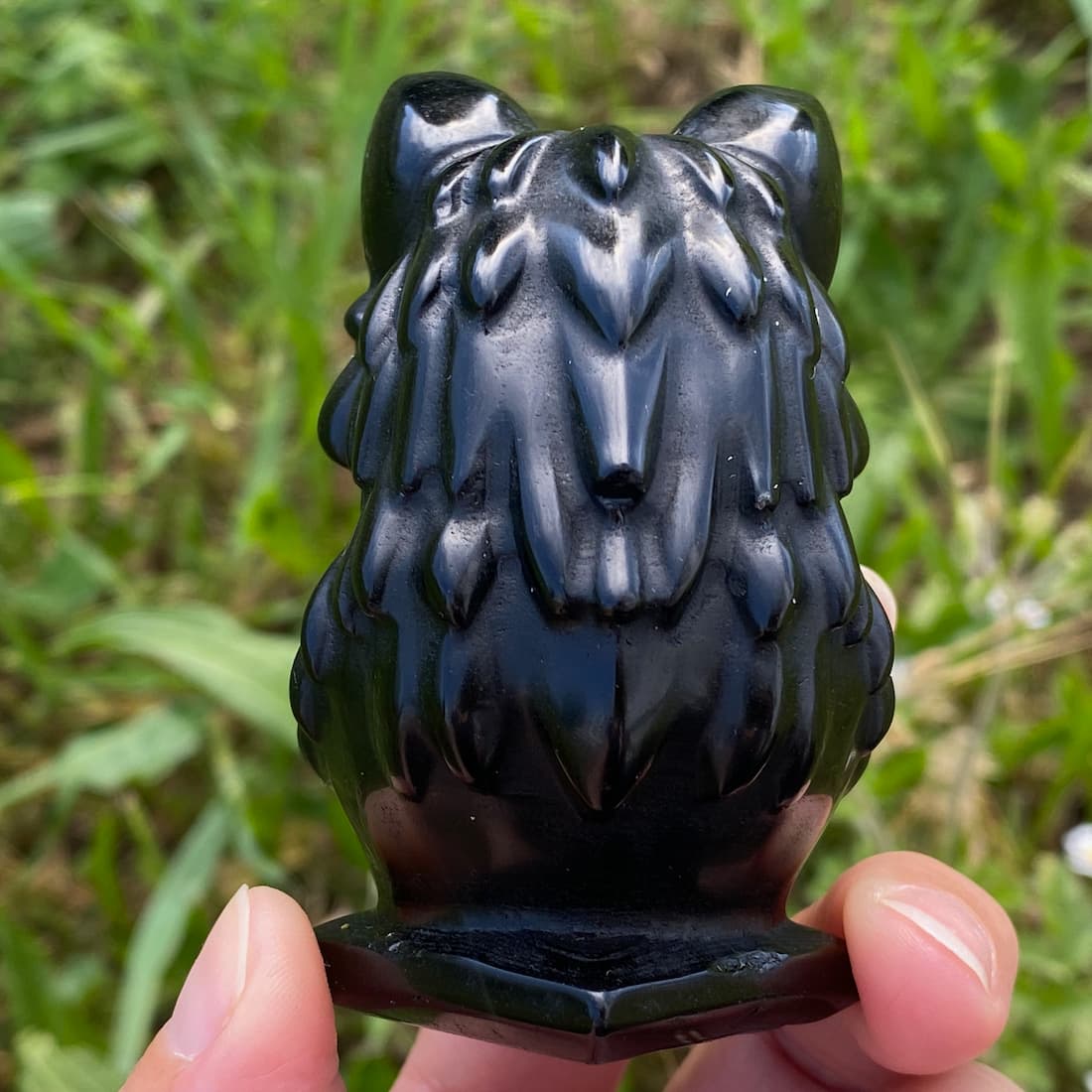 Buste de loup en obsidienne noire vu de dos, sculpture sur socle en pierre volcanique