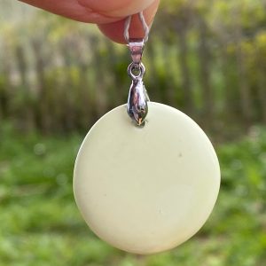 Gros plan d'un pendentif artisanal en pierre de chrysoprase citron naturelle. La pierre est taillée en goutte lisse, suspendue à une fine chaîne en argent massif. La couleur de la chrysoprase est un vert-jaune acidulé lumineux et uniforme, se détachant sur un fond blanc pur épuré.